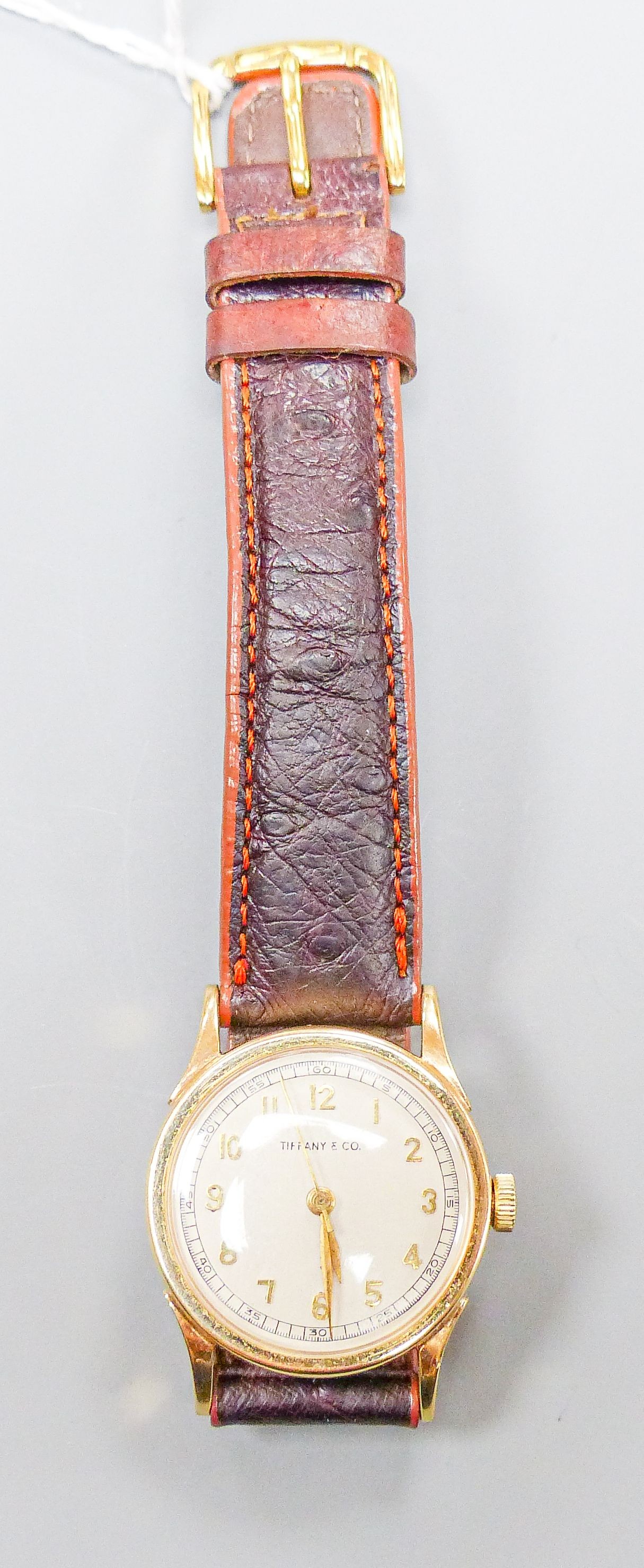 A lady's 14k Tiffany & Co manual wind wrist watch, on associated leather strap, case diameter 27mm, gross weight 28.8 grams.